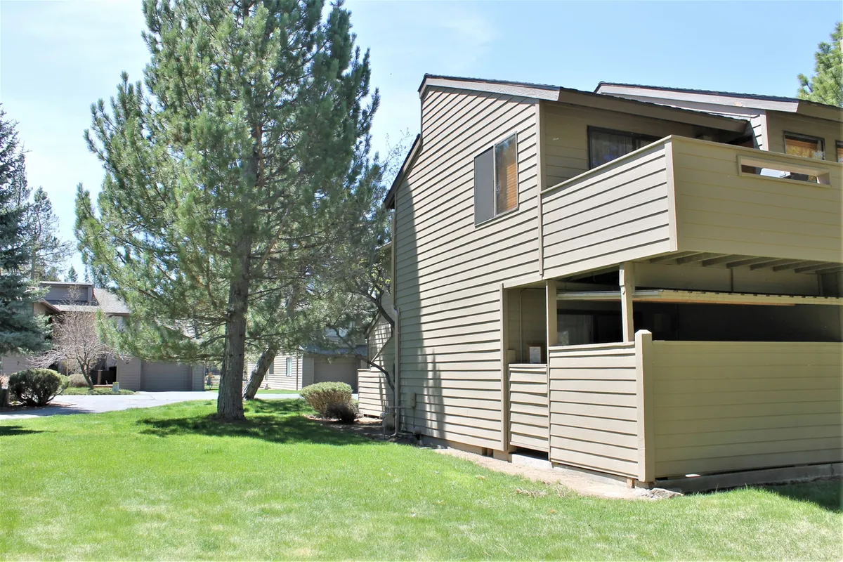A peaceful exterior shot highlighting the condo building’s facade, a private balcony, and mature trees. The scene invites guests to imagine relaxing outdoors, enjoying morning coffee, or gathering with friends amid natural beauty.