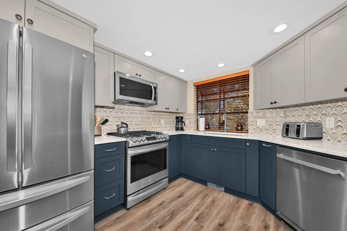 A stylish kitchen featuring stainless steel appliances, striking blue cabinetry, and a textured backsplash. The kitchen is ready for culinary adventures or casual breakfasts, with plenty of counter space and contemporary flair.